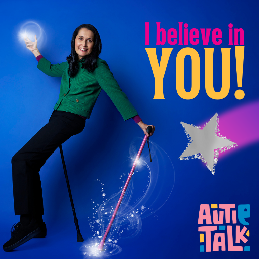 Image is of Kory Sherland, founder of Autie Talk, a white woman with dark brown hair. She is wearing a green jacket with gold buttons. She is sitting on a 'flipstick' an holding a pink walking stick with glitter coming off it. A silver star is on the right of the stick. There is a ball of light coming out of her right hand. Words on the top right say: I believe in you! Autie Talk logo is on the bottom right corner. 